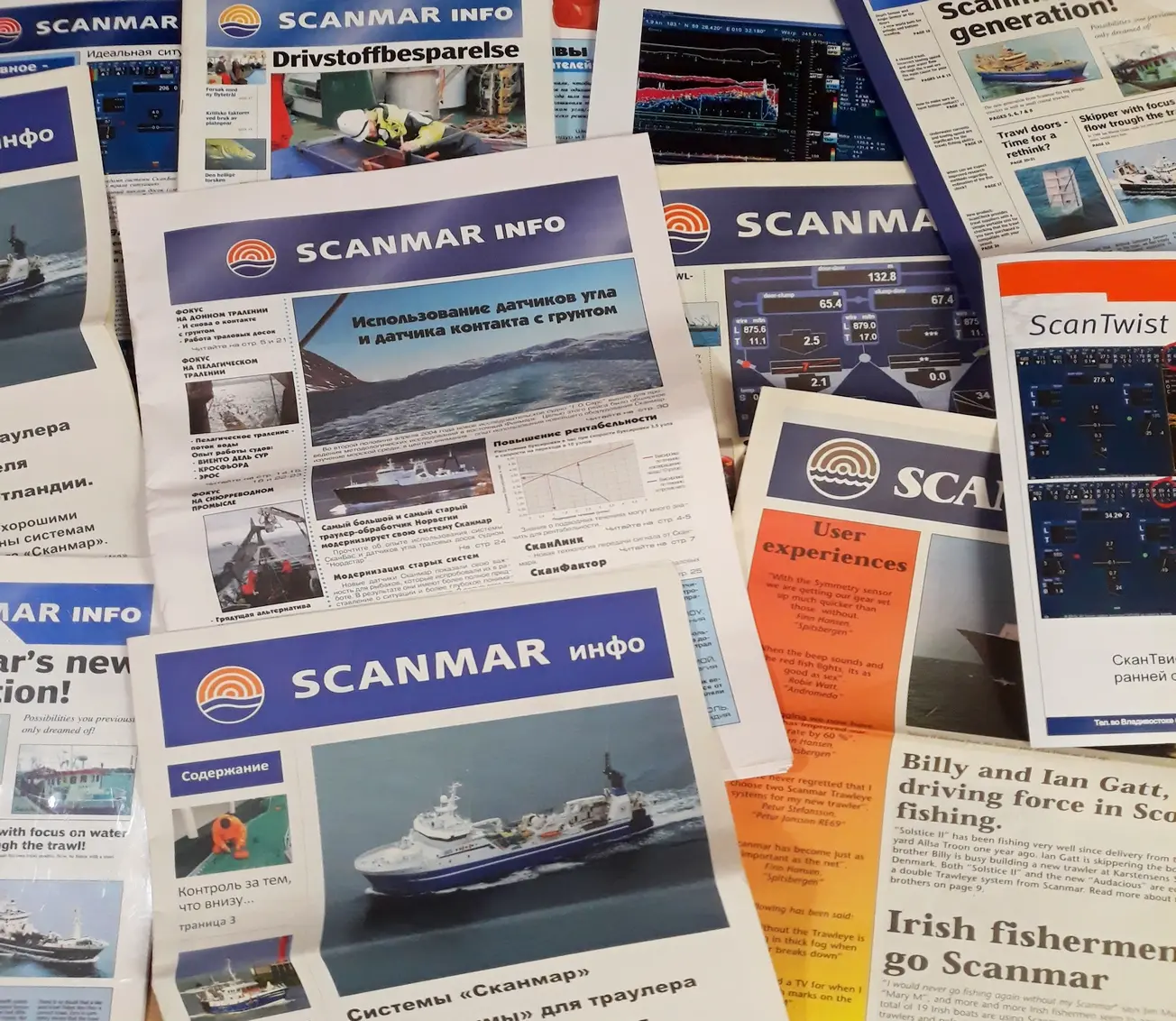 Editions of the Scanmar Info newspaper spread out on a table